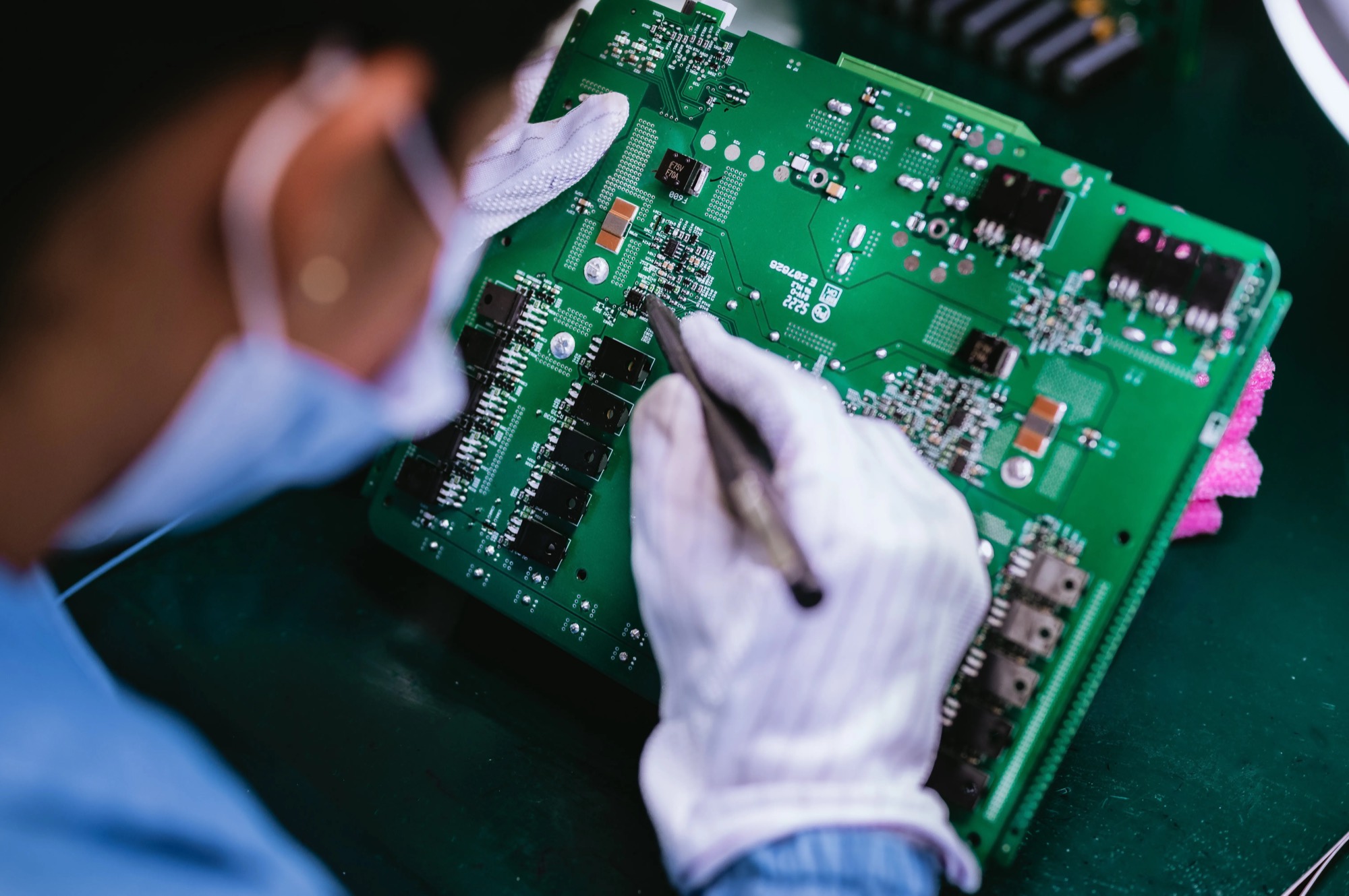 Gloved technician inspecting an electronic board