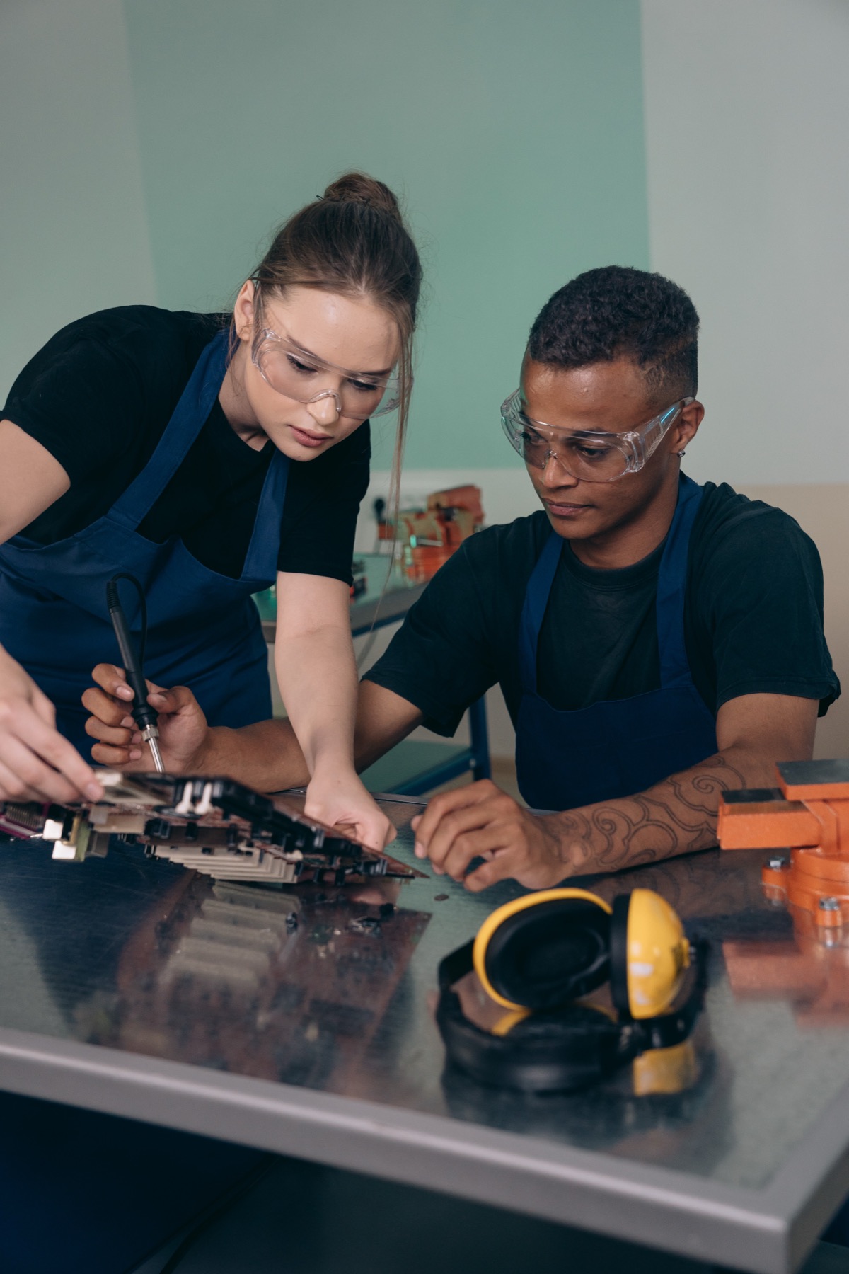 Two technicians working on an electronic board at a workbench